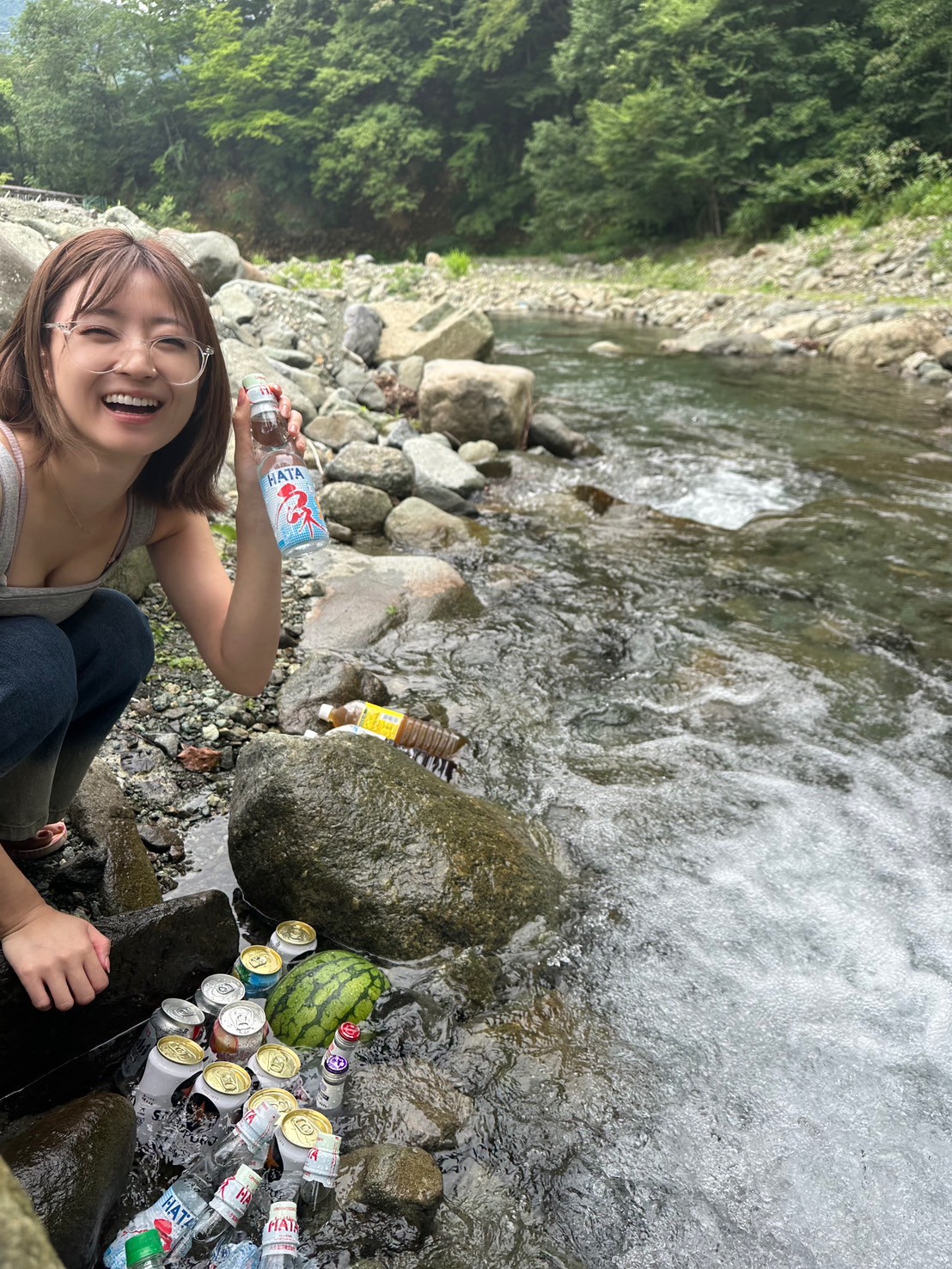 【関東】神奈川県相模原市のテントサウナパーク In 高瀬野でBBQを楽しむ女性が川沿いで飲み物を持っている様子